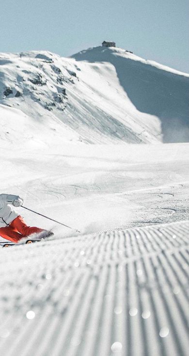Ein Mann fährt mit seinen Skiern eine Skipiste im Skigebiet Drei Zinnen hinunter