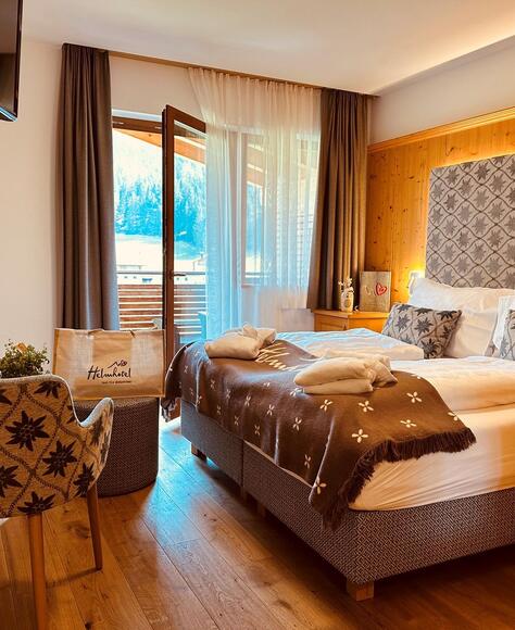 Komfortzimmer Cosy mit Doppelbett, Sessel, Minikühlschrank und Balkon Richtung Garten