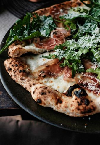 Pizza mit Rohschinken, Rucola und Parmesan