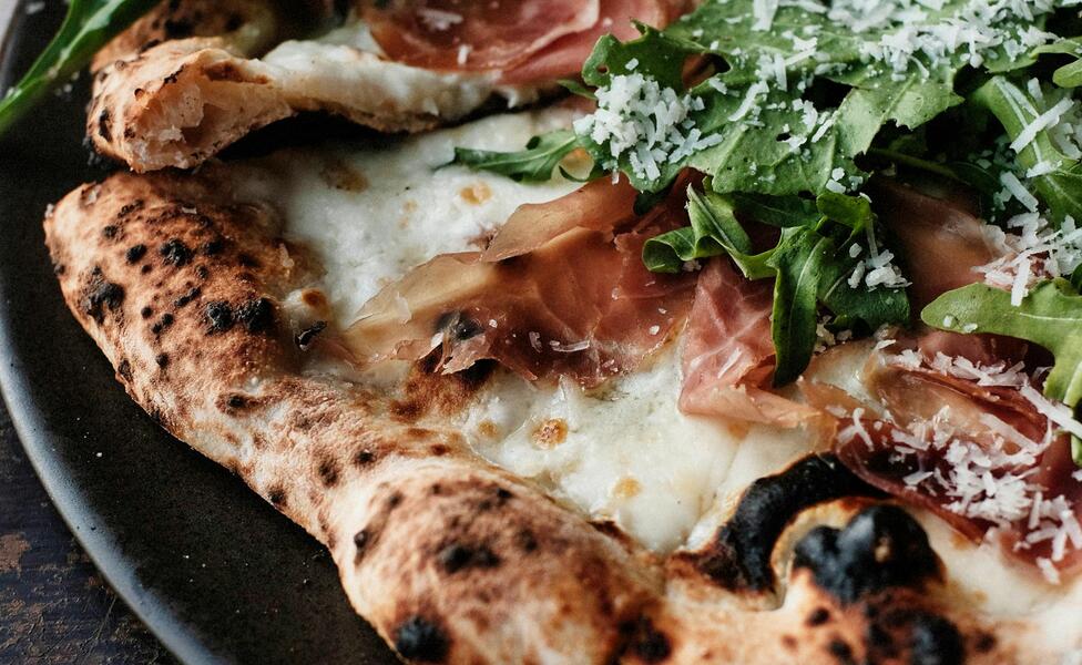 Pizza mit Rohschinken, Rucola und Parmesan