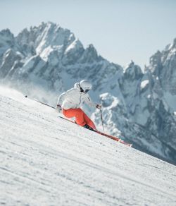 Ein Mann fährt mit seinen Skiern eine Skipiste im Skigebiet Drei Zinnen hinunter