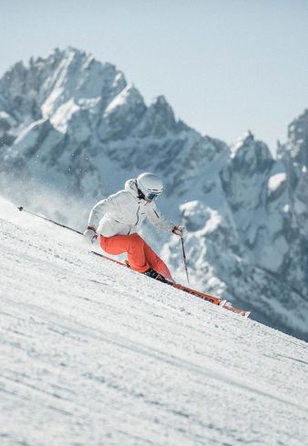 Ein Mann fährt mit seinen Skiern eine Skipiste im Skigebiet Drei Zinnen hinunter