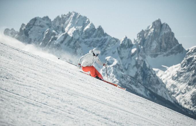 Ein Mann fährt mit seinen Skiern eine Skipiste im Skigebiet Drei Zinnen hinunter