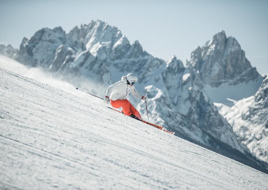 Un uomo scende una pista da sci con i suoi sci nel comprensorio sciistico delle Drei Zinnen