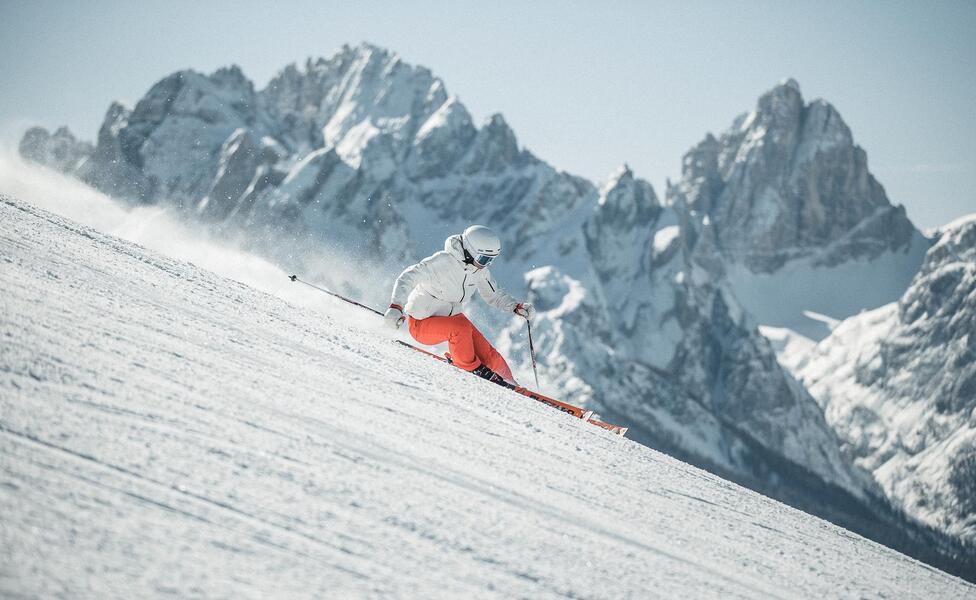A man is skiing down a ski slope in the Drei Zinnen ski area