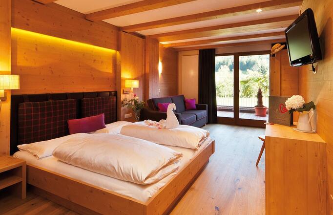 "Family Holzduft" room with double bed, sofa, bunk bed for children, TV and balcony facing the garden