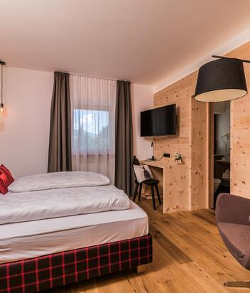 Cirmolino room with bed, TV, mini fridge and window facing the street / the village of Versciaco