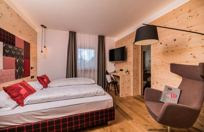 Zimmer Cirmolino mit Bett, TV, Minikühlschrank und Fenster zur Straße / zum Dorf Versciaco