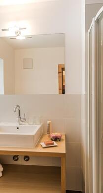 Badezimmer mit Dusche, Waschbecken und Fenster zur Straße / nach Versciaco