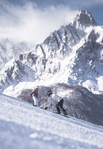 Ein Mann lernt einem Kind das Skifahren im Skigebiet Drei Zinnen