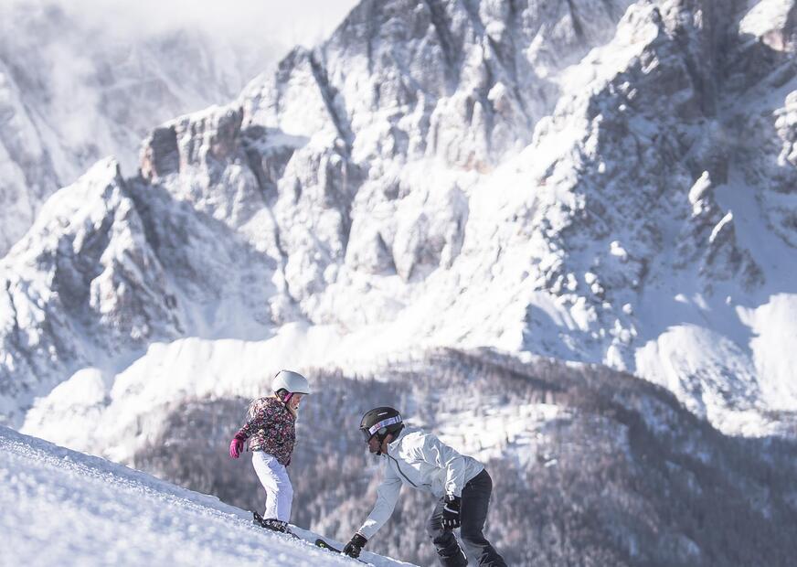 Un uomo insegna a un bambino a sciare nel comprensorio sciistico delle tre cime