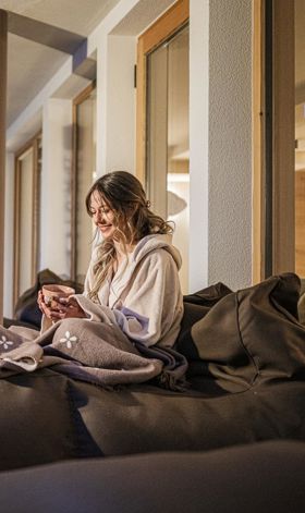 Una donna è sdraiata su una sdraio e beve una tazza di tè