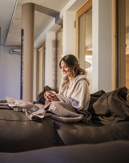 Una donna è sdraiata su una sdraio e beve una tazza di tè