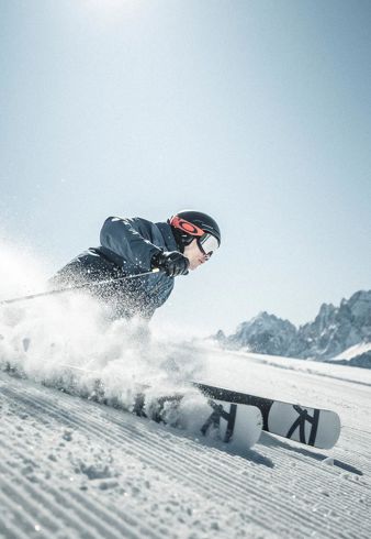 Ein Mann fährt mit seinen Skiern eine Skipiste im Skigebiet Drei Zinnen hinunter