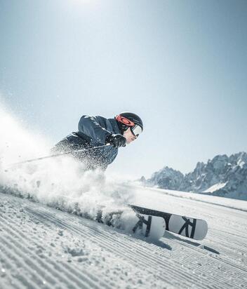 Ein Mann fährt mit seinen Skiern eine Skipiste im Skigebiet Drei Zinnen hinunter