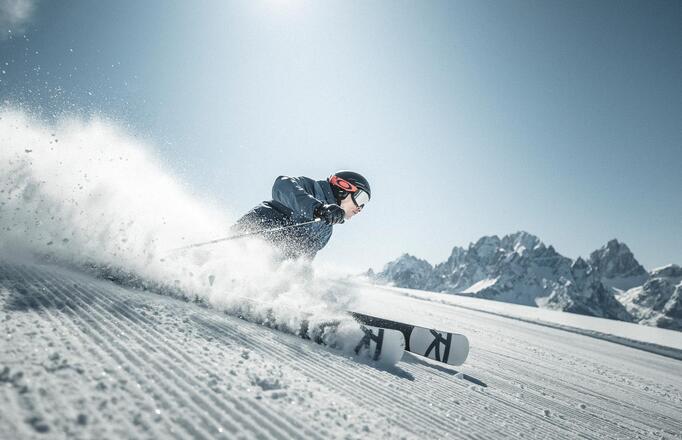 Ein Mann fährt mit seinen Skiern eine Skipiste im Skigebiet Drei Zinnen hinunter