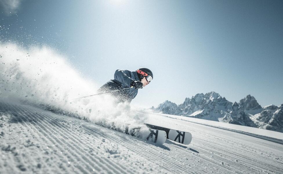 Un uomo scende una pista da sci con i suoi sci nel comprensorio sciistico delle tre cime