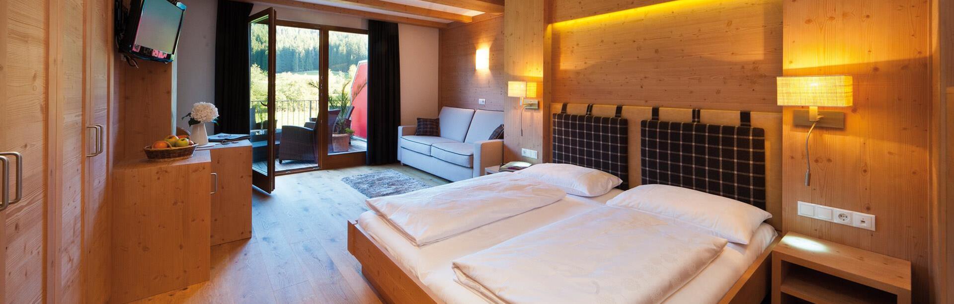 Komfortzimmer mit Doppelbett, Sofa, Balkon Richtung Garten, Schrank, Minikühlschrank und TV
