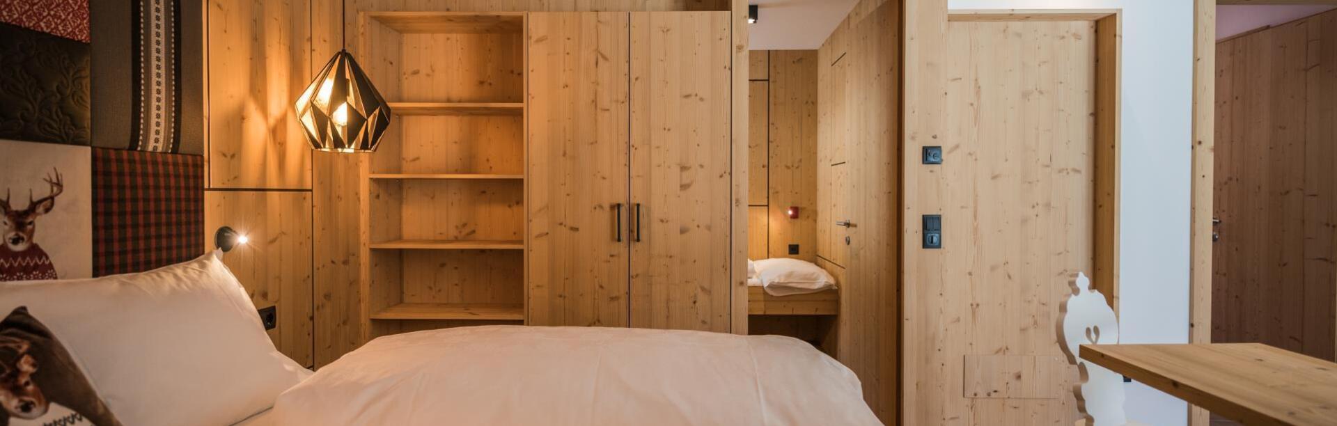 Zimmer „Family Flora“ mit Doppelbett, Bücherregal, Kleiderschrank, separatem Kinderbereich und Schreibtisch