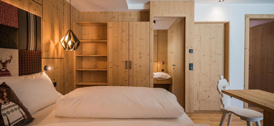 Zimmer „Family Flora“ mit Doppelbett, Bücherregal, Kleiderschrank, separatem Kinderbereich und Schreibtisch