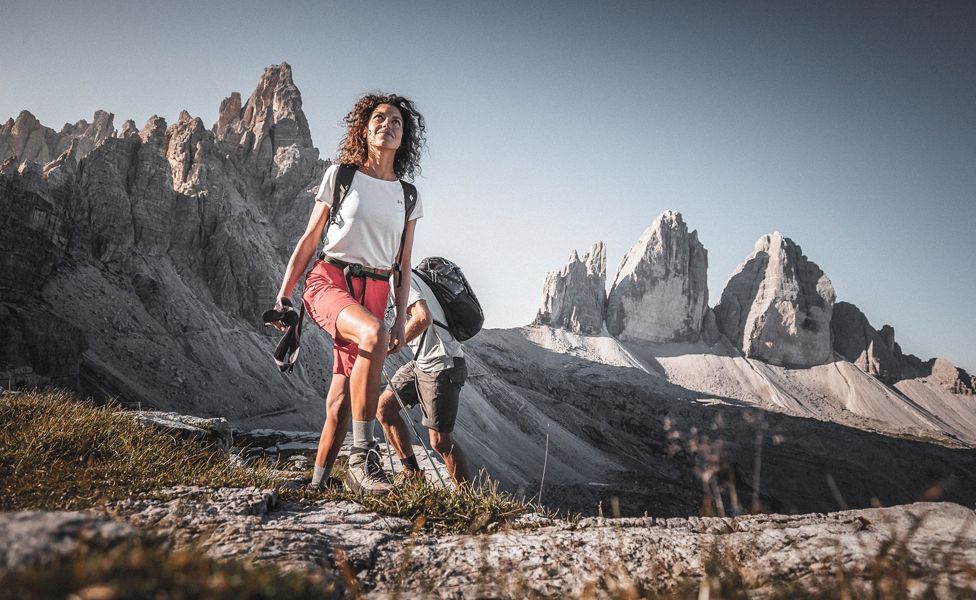 Una donna e un uomo in cammino, con le Tre Cime sullo sfondo