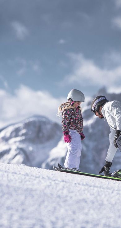 Un uomo insegna a un bambino a sciare nel comprensorio sciistico delle tre cime