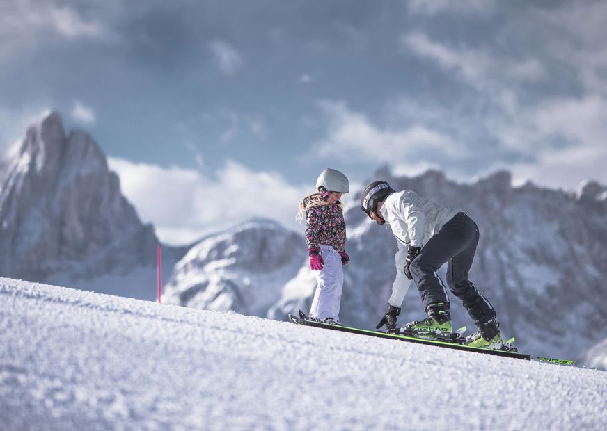 Ein Mann lernt einem Kind das Skifahren im Skigebiet Drei Zinnen