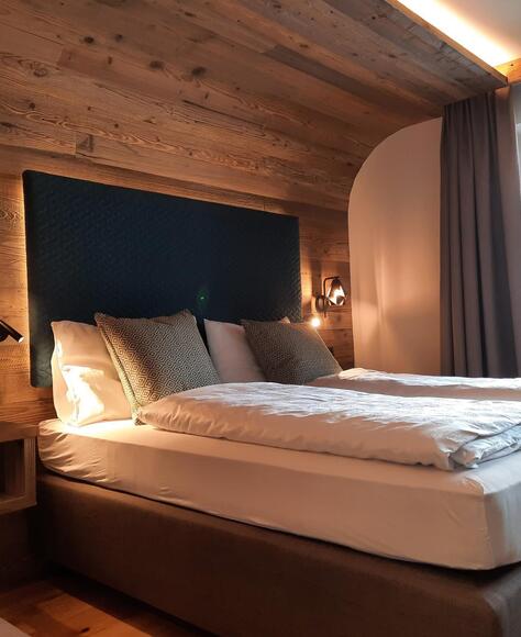 Dolomiten-Suite aus Holz mit Bett, Sofa und Balkon Richtung Garten
