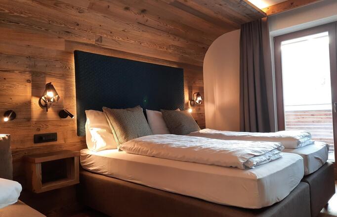 Wooden Dolomites Suite with bed, sofa and garden-side balcony