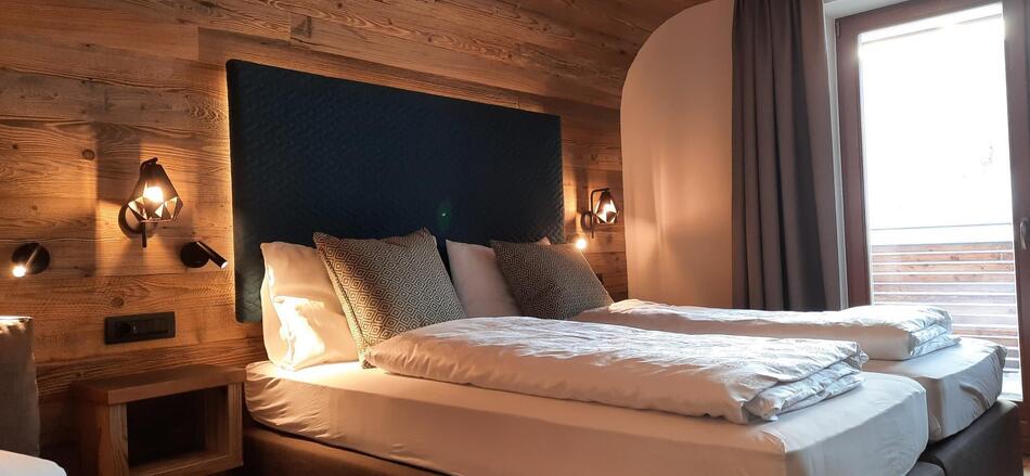 Dolomiten-Suite aus Holz mit Bett, Sofa und Balkon Richtung Garten