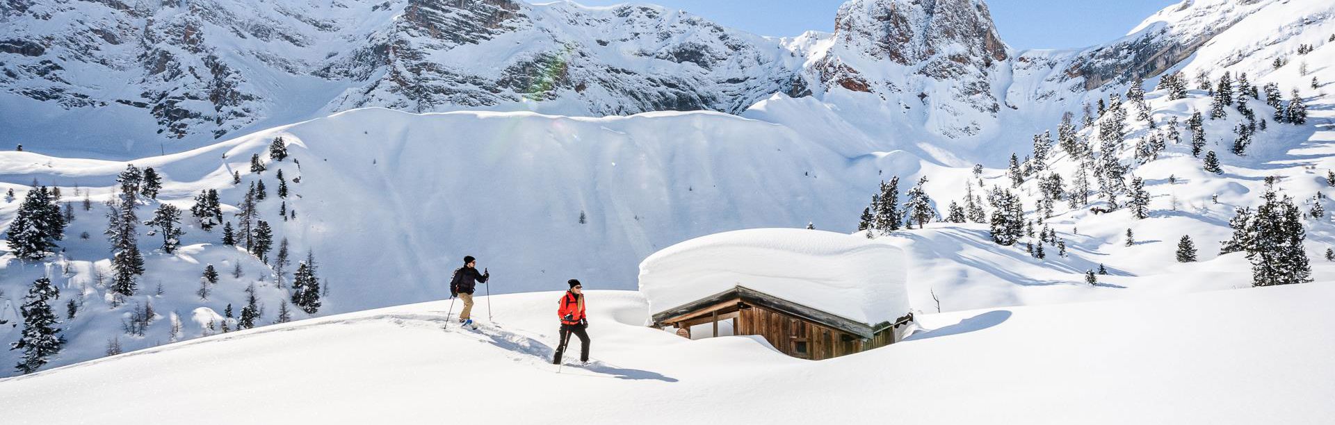 Zwei Personen beim Schneeschuhwandern in Prags, umgeben von den Dolomiten