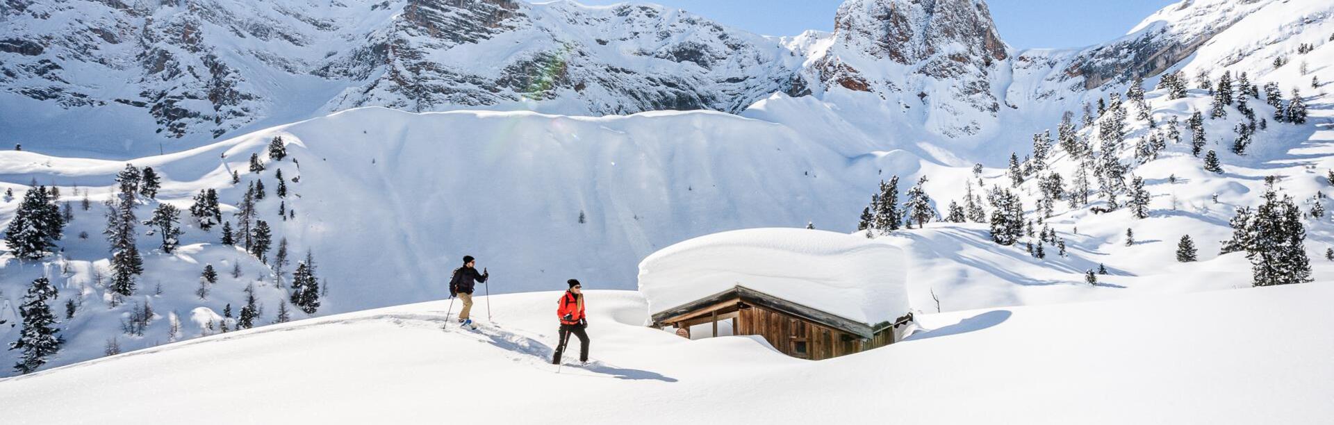 Due persone praticano escursionismo con le ciaspole a Braies, circondate dalle dolomiti
