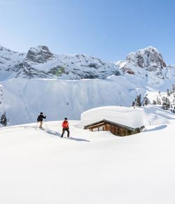 Zwei Personen beim Schneeschuhwandern in Prags, umgeben von den Dolomiten