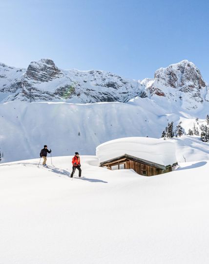 Zwei Personen beim Schneeschuhwandern in Prags, umgeben von den Dolomiten