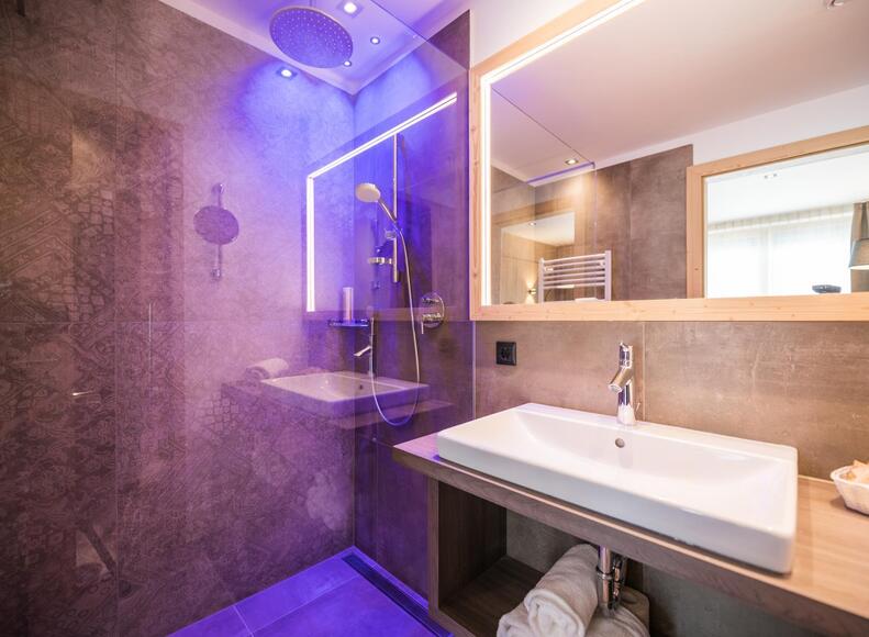 Badezimmer des Family-Zimmers Flora mit Waschbecken, Spiegel und Dusche