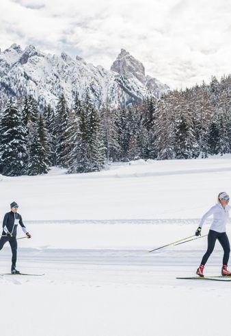 Un uomo e una donna che fanno sci di fondo nelle Dolomiti