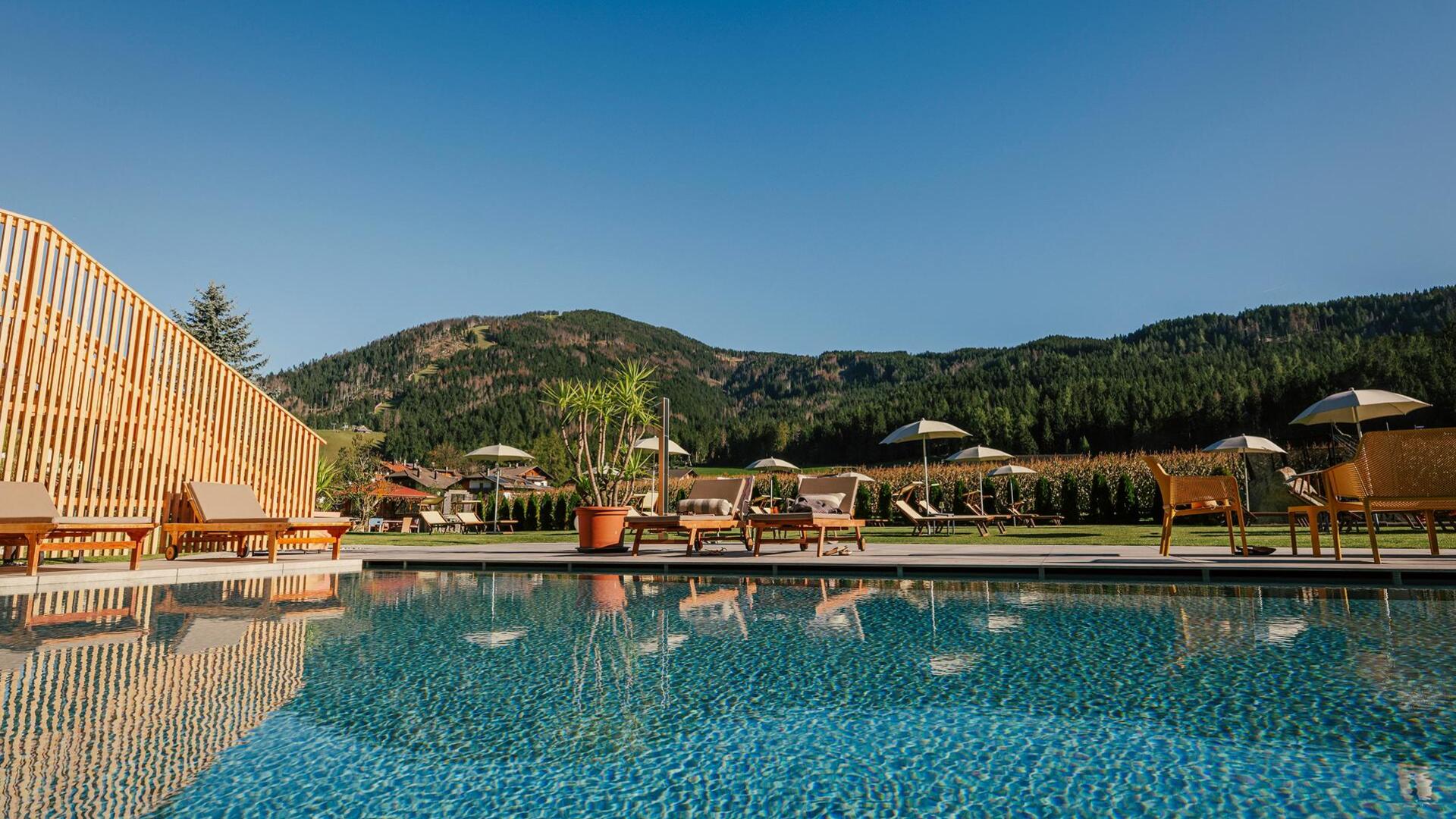 Außenpool des Helmhotels mit Liegen und dem Helm im Hintergrund