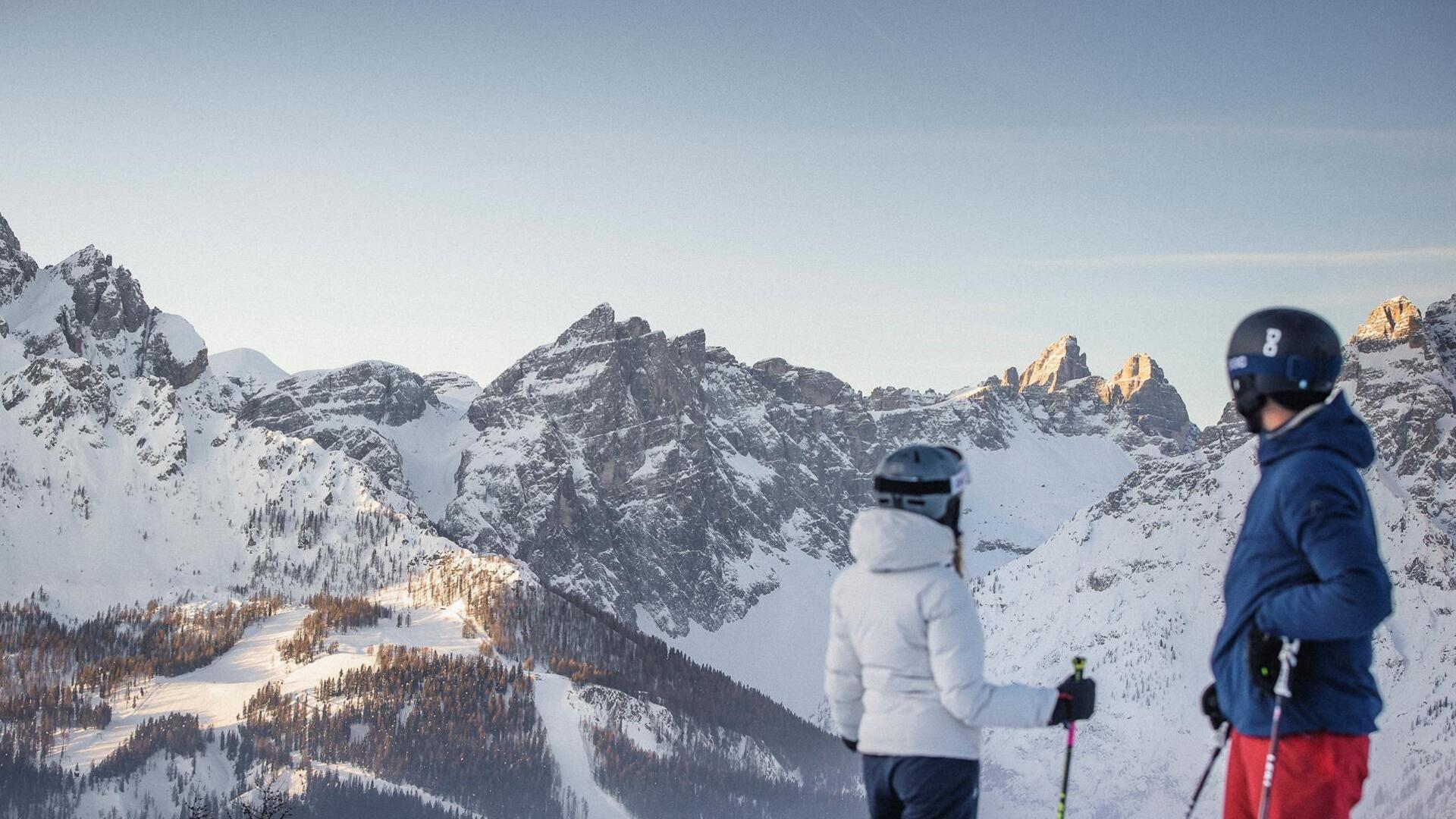 Ein Mann und eine Frau in Skikleidung schauen auf die Dolomiten im Skigebiet Drei Zinnen.