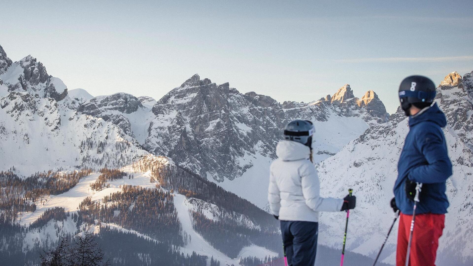 Ein Mann und eine Frau in Skikleidung schauen auf die Dolomiten im Skigebiet Drei Zinnen.