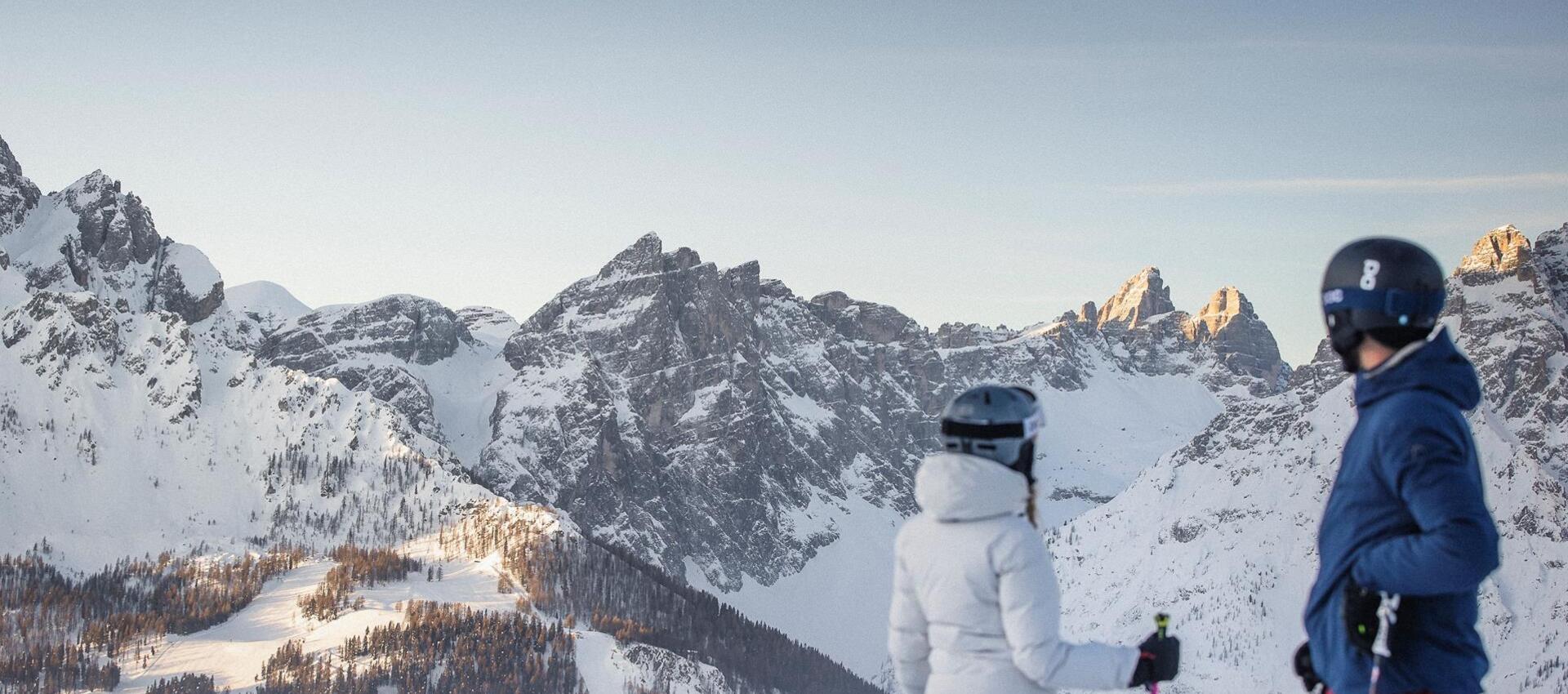 Ein Mann und eine Frau in Skikleidung schauen auf die Dolomiten im Skigebiet Drei Zinnen.