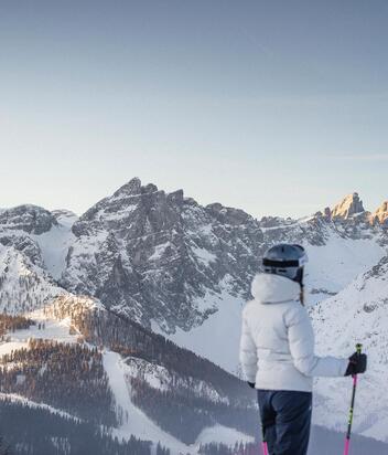 Ein Mann und eine Frau in Skikleidung schauen auf die Dolomiten im Skigebiet Drei Zinnen.
