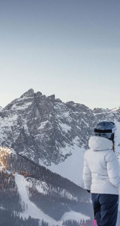 Un uomo scende una pista da sci con i suoi sci nel comprensorio sciistico delle tre cime