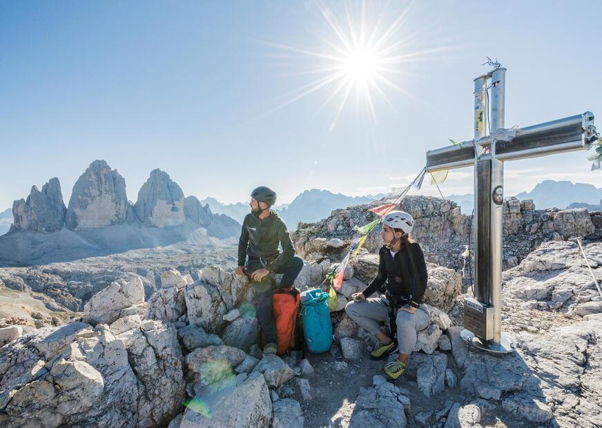 Una donna e un uomo in cammino, con le Tre Cime sullo sfondo